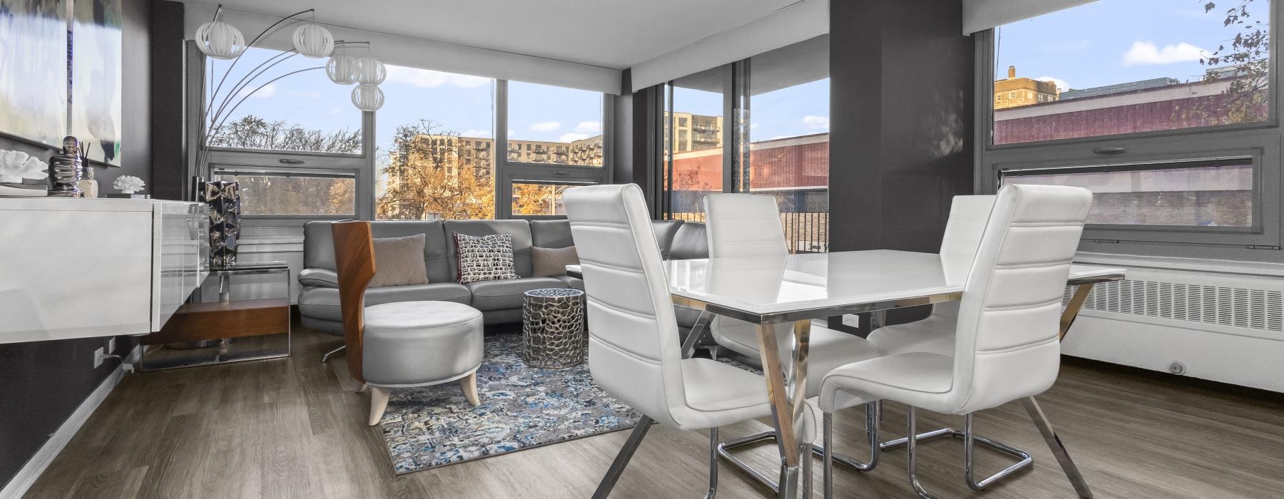 a room with a table chairs and a window with a view of the city